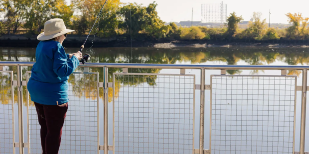 Woman fishing on bridge.