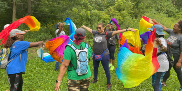 Women gathered in a circle waving rainbow colored fabric