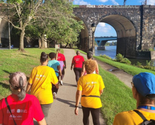 Group of women walking in colorful shirts on a trail along a river