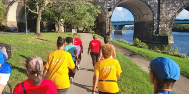 Group of women walking in colorful shirts on a trail along a river