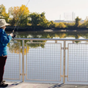 woman in a blue shirt and tan hat fishing off a pier