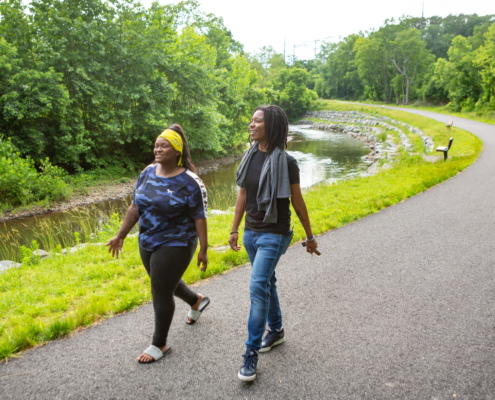 A young man and women wearing casual clothes walking on the paved Chester Creek Trail.