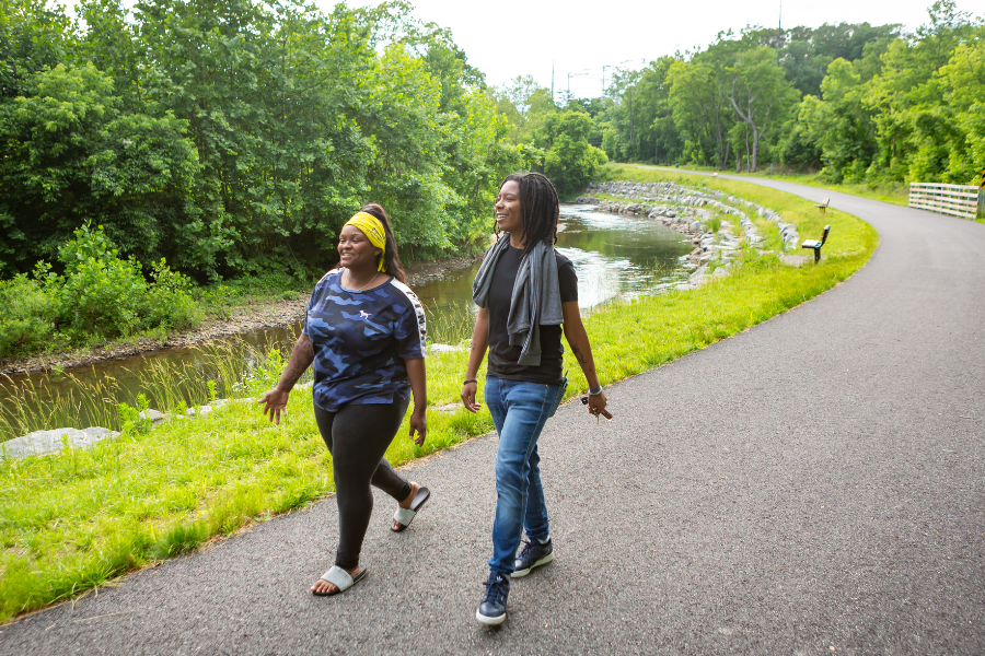 A young man and women wearing casual clothes walking on the paved Chester Creek Trail.