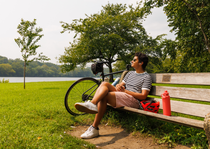 man sitting on a bench along the Schuylkill River Trail with his bike next to him