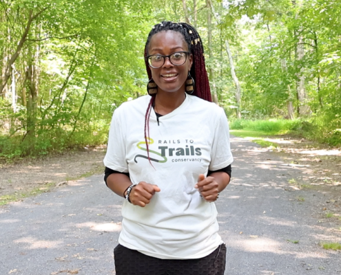 Black women with braids and glasses standing on a nature trail
