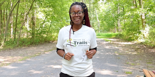 Black women with braids and glasses standing on a nature trail