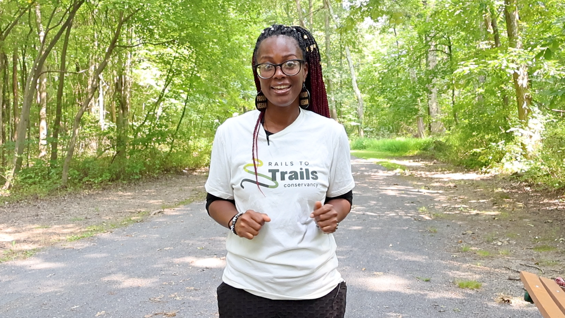 Black women with braids and glasses standing on a nature trail