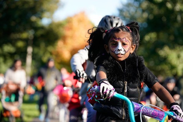 young girl riding a bike in a halloween costume