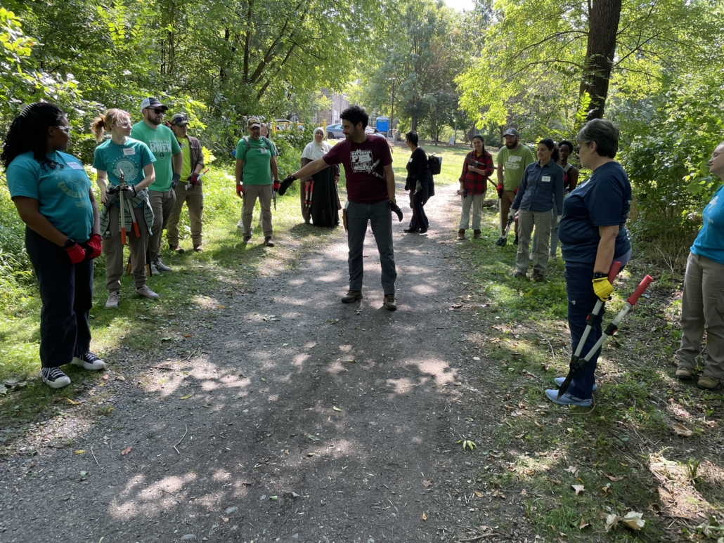 Man standing in the middle of a gravel trail pointing while other people are circled around him 