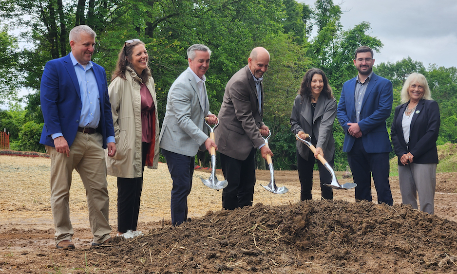 officials digging shovels into a pile of dirt breaking new ground on the trail