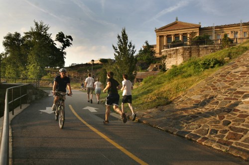 cyclist and runners on the Schuylkill River Trail behind the Philadelphia Museum of Art